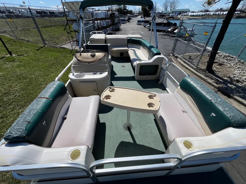 Slide: The Image of 1998 Fisher Freedom 200 DLX pontoon boat with spacious seating and table, docked by the water. - 11