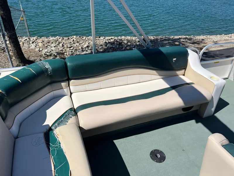 Slide: The Image of 1998 Fisher Freedom 200 DLX boat interior with green and beige seating by the water. - 17