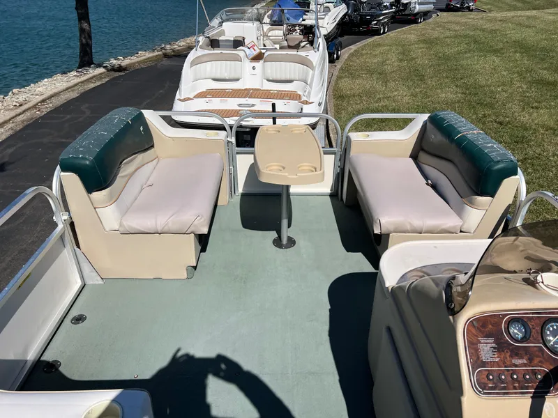 Slide: The Image of 1998 Fisher Freedom 200 DLX pontoon boat interior with seating and table, docked by the water. - 21