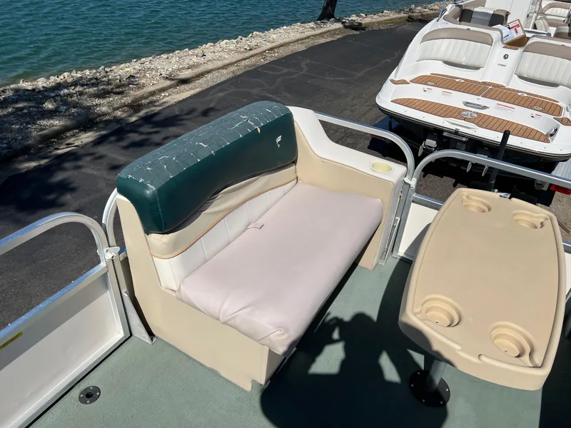 Slide: The Image of 1998 Fisher Freedom 200 DLX pontoon boat interior with seating and table by the water. - 22