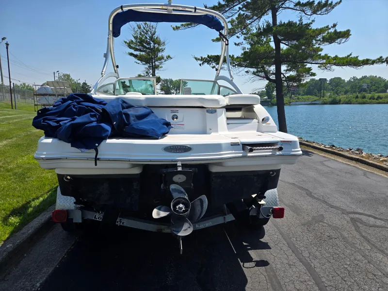 Slide: The Image of 2011 Chaparral 196 SSi boat parked by a lakeside, rear view with propeller visible. - 2