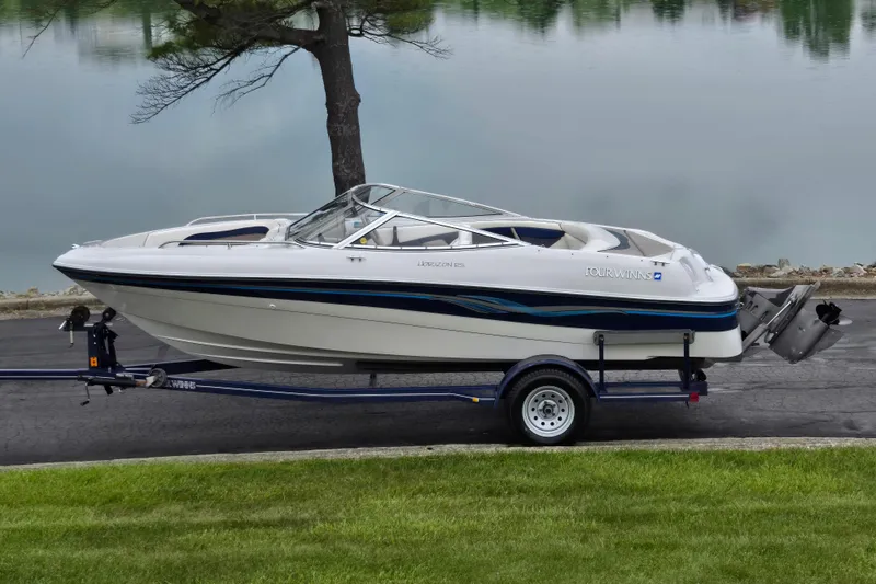 The Image of 1998 Four Winns 180 Horizon boat on trailer by a lake. - 0