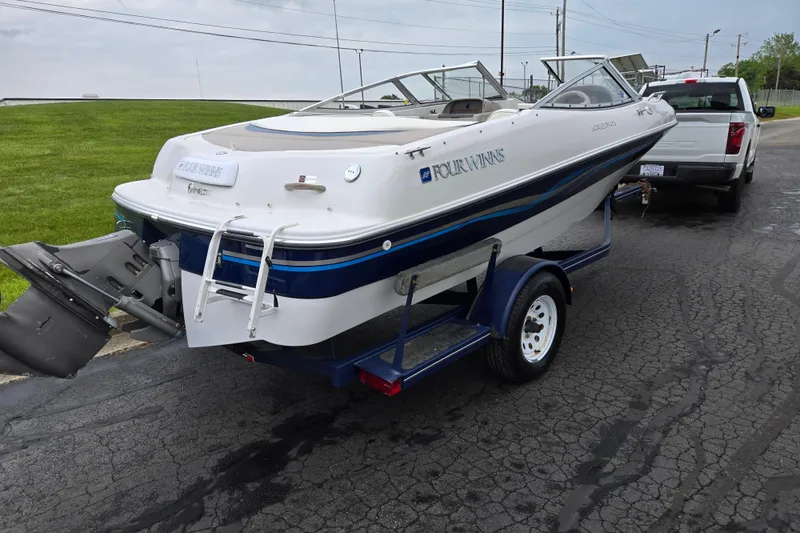 Slide: The Image of 1998 Four Winns 180 Horizon boat on trailer, parked near a pickup truck. - 3