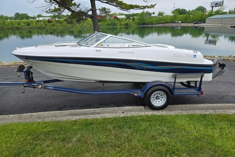 Slide: The Image of 1998 Four Winns 180 Horizon boat on trailer by a lake. - 9