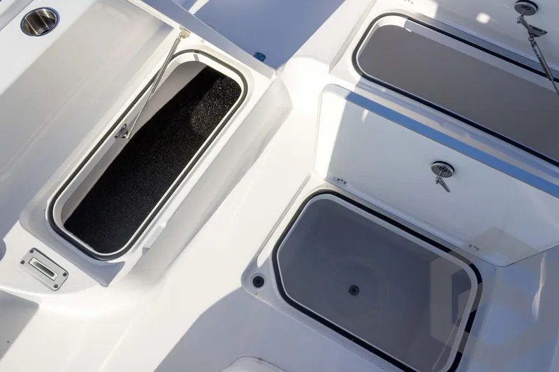 Slide: The Image of 2026 Caymas 26 HB boat storage compartments with open and closed lids. - 32