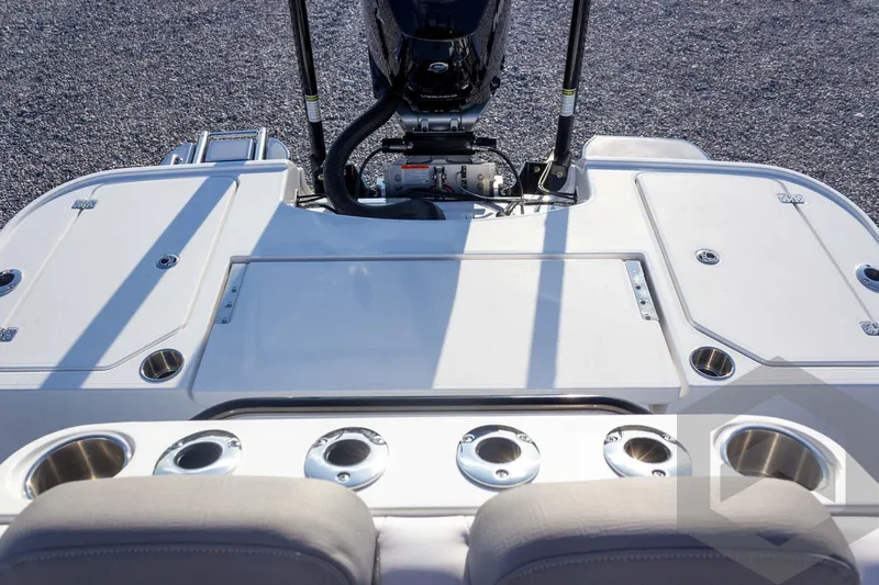 Slide: The Image of 2026 Caymas 26 HB boat deck with motor, cup holders, and storage compartments. - 57