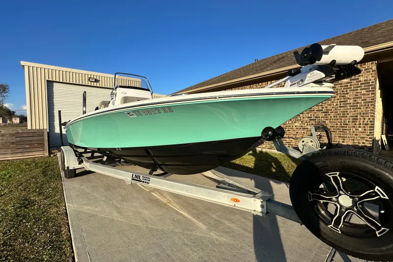 Slide: The Image of 2023 Sportsman Tournament 234 Bay Boat on trailer, parked outside a garage. - 11