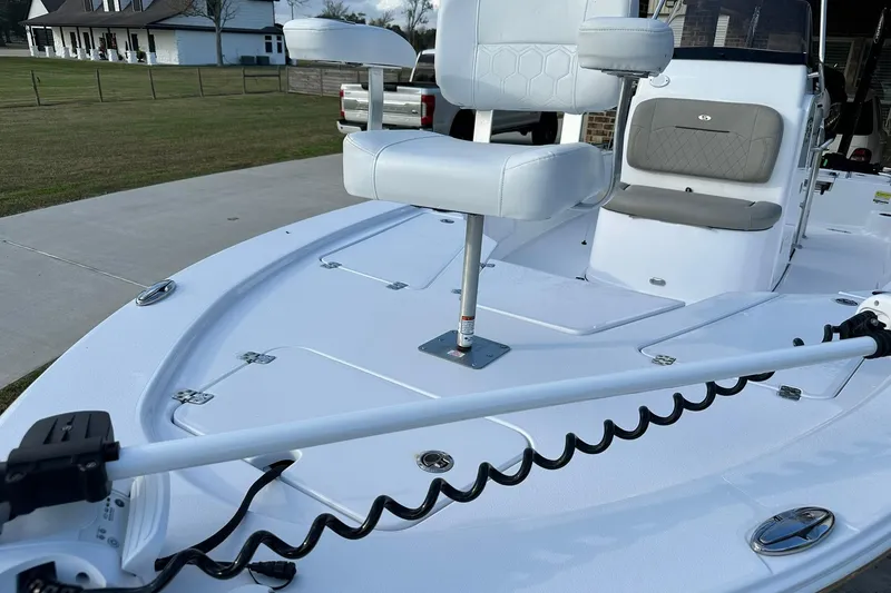 Slide: The Image of 2023 Sportsman Tournament 234 Bay Boat with seating and trolling motor, parked near a house. - 16