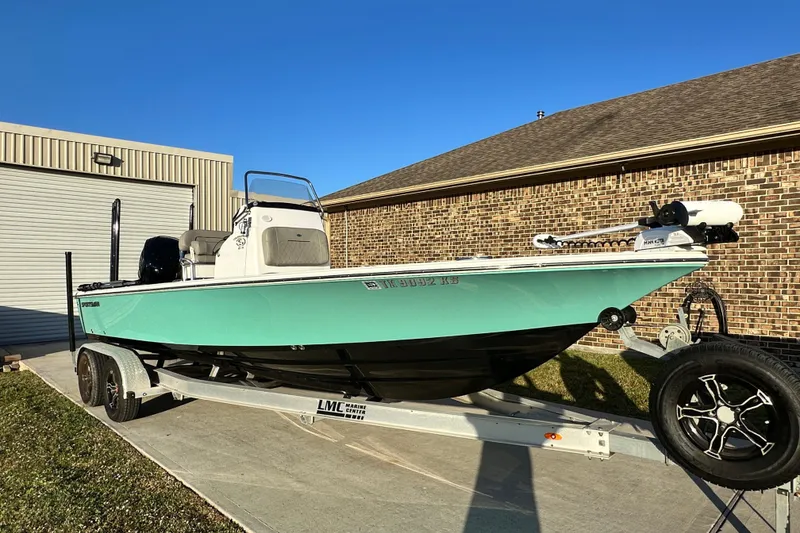 Slide: The Image of 2023 Sportsman Tournament 234 Bay Boat on trailer, parked outside a garage. - 2
