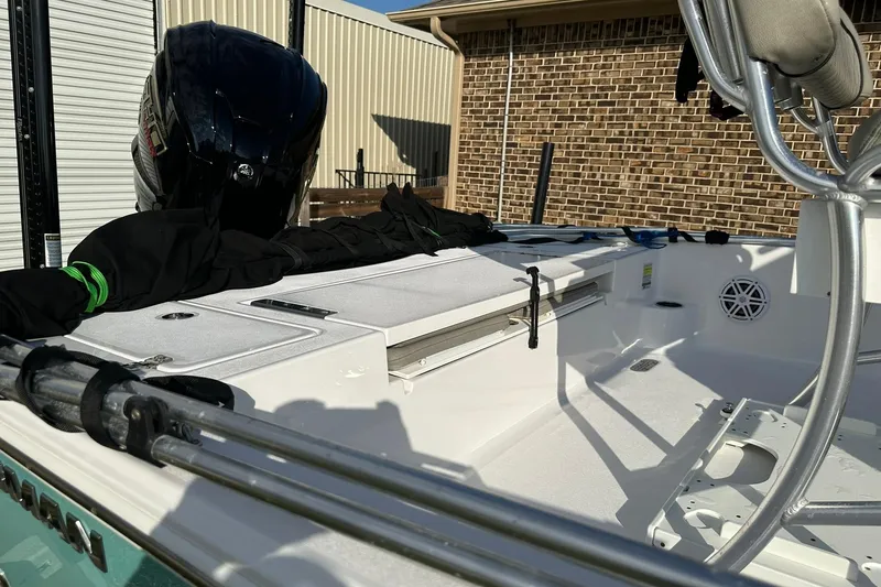 Slide: The Image of 2023 Sportsman Tournament 234 Bay Boat interior with fishing gear and motor, docked near brick building. - 29