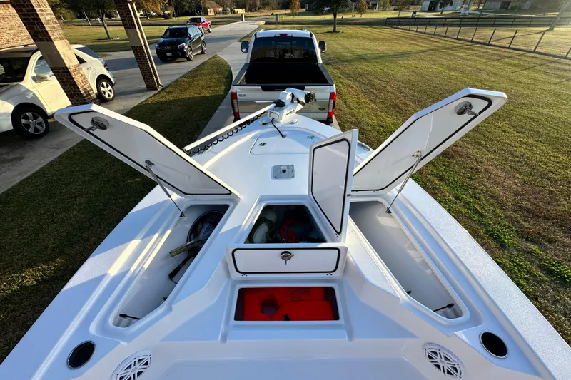 Slide: The Image of 2023 Sportsman Tournament 234 Bay Boat with open storage compartments, parked near a truck. - 41