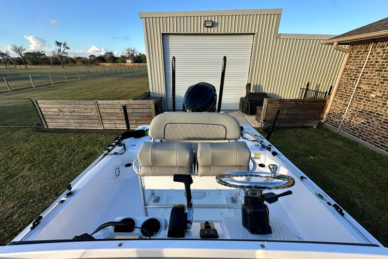 Slide: The Image of 2023 Sportsman Tournament 234 Bay Boat parked near a metal building and wooden fence. - 59