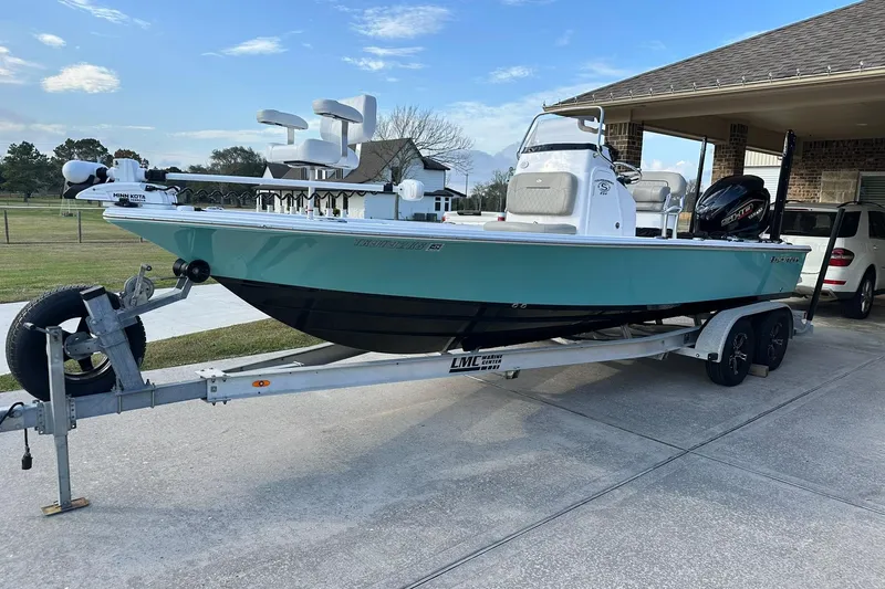 Slide: The Image of 2023 Sportsman Tournament 234 Bay Boat on trailer, parked in driveway, clear sky background. - 6