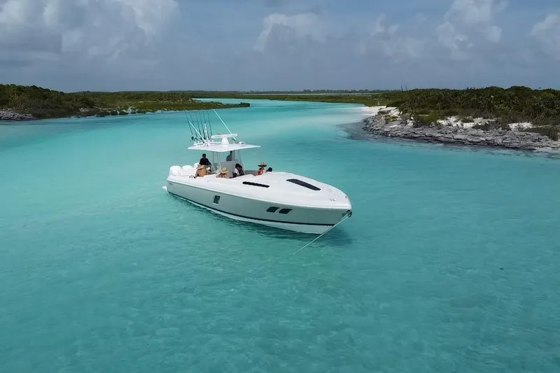 The Image of 2015 Intrepid 400 Cuddy boat anchored in clear turquoise waters, surrounded by lush greenery. - 0