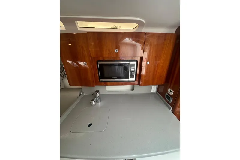 Slide: The Image of 2015 Intrepid 400 Cuddy kitchen area with microwave and wooden cabinets. - 9