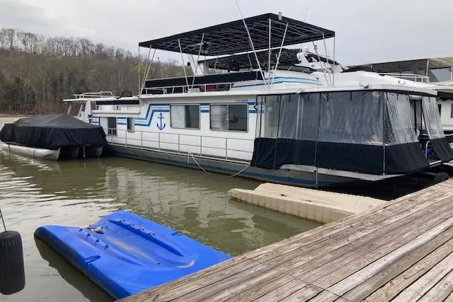 The Image of 1981 Sumerset houseboat docked on a lake, featuring blue accents and covered deck. - 0