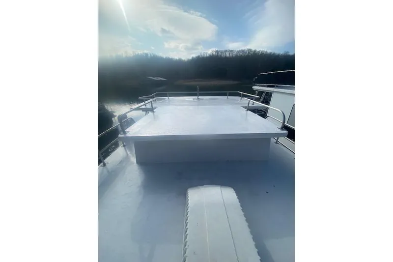 Slide: The Image of 1981 Sumerset houseboat deck with railing, under a bright sky and serene water backdrop. - 17