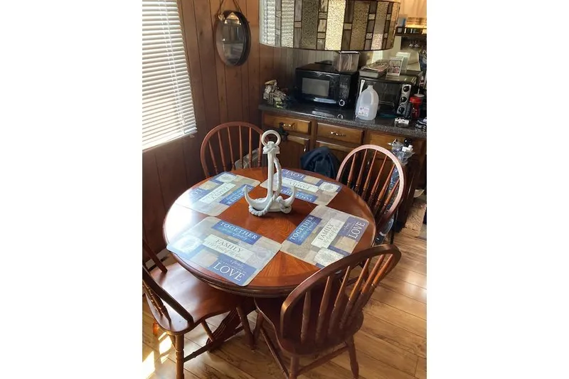 Slide: The Image of 1981 Sumerset houseboat dining area with wooden table, chairs, and nautical decor. - 5