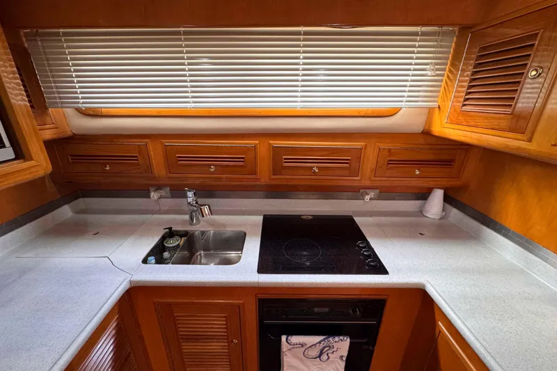 Slide: The Image of 2007 Albin 45 Command Bridge kitchen with stove, sink, and wooden cabinets. - 22