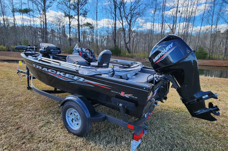 Slide: The Image of 2025 Tracker Pro Guide V-16 SC boat with Mercury engine on grassy area. - 2