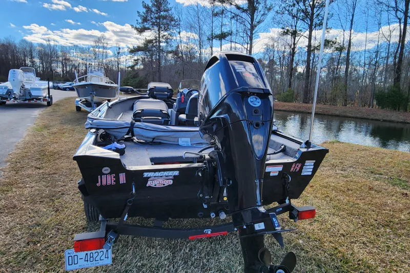 Slide: The Image of 2025 Tracker Pro Guide V-16 SC boat with motor, parked near a serene lake. - 3