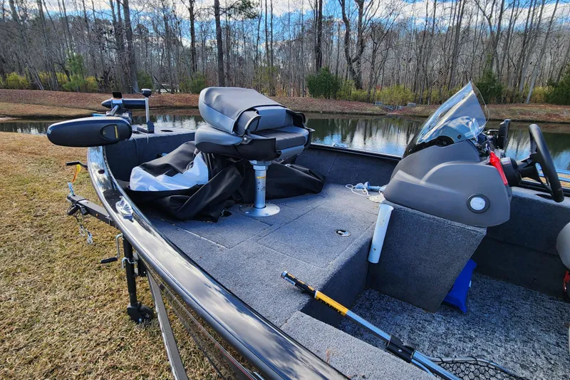 Slide: The Image of 2025 Tracker Pro Guide V-16 SC boat interior by a serene lake. - 9