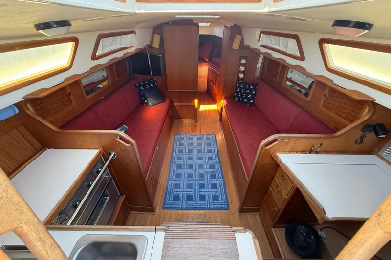Slide: The Image of 1986 Sabre 30 MKIII yacht interior with red seating, wooden cabinetry, and blue rug. - 29