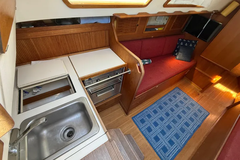 Slide: The Image of 1986 Sabre 30 MKIII yacht interior with kitchen, sink, stove, and red seating area. - 31