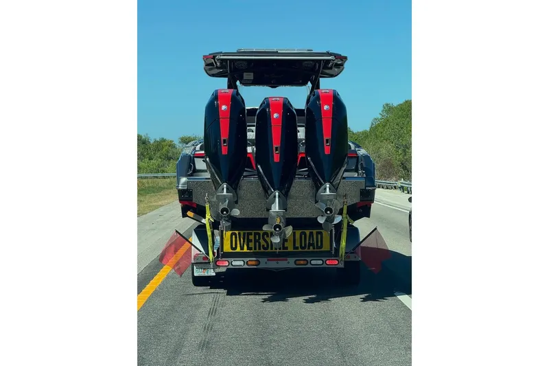 Slide: The Image of 2025 Nor-Tech 390 Sport Center Console on trailer, marked "Oversize Load," with triple outboard engines. - 25