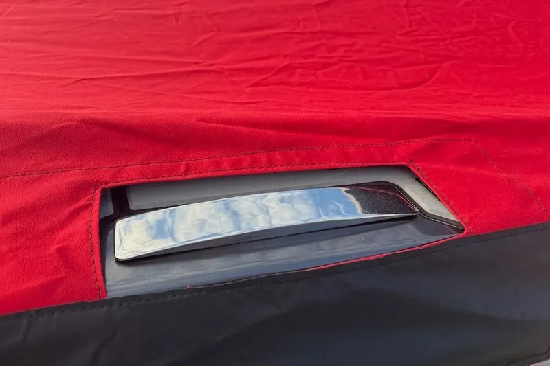 Slide: The Image of Red cover on 2025 Nor-Tech 390 Sport Center Console boat, partially revealing chrome detail. - 26