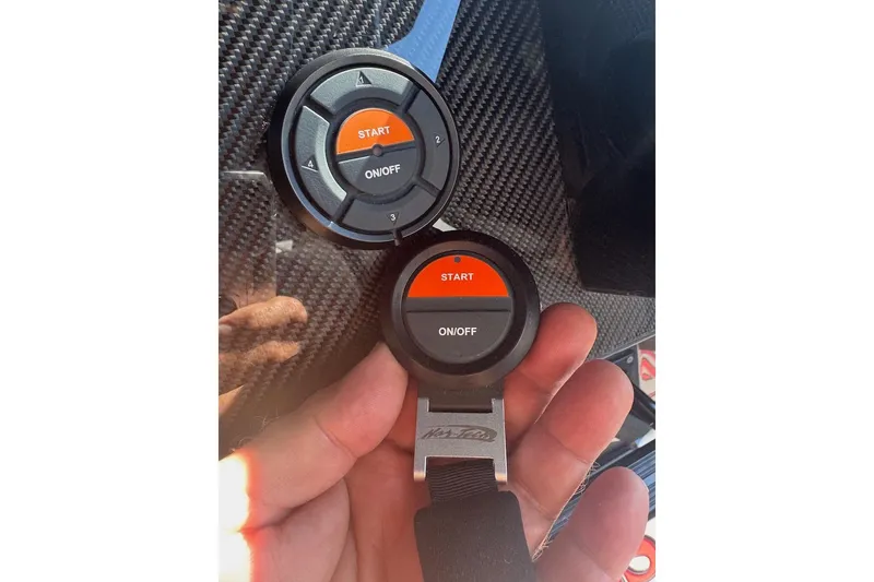 Slide: The Image of Hand holding Nor-Tech 390 Sport Center Console 2025 start button on carbon fiber background. - 28