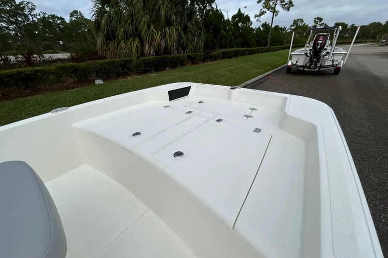 Slide: The Image of 2026 Mako Pro Skiff 15 CC boat on trailer, parked near lush greenery. - 5