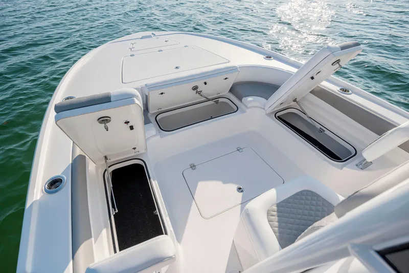 Slide: The Image of Caymas 26 HB 2026 boat with open storage compartments on calm water. - 11