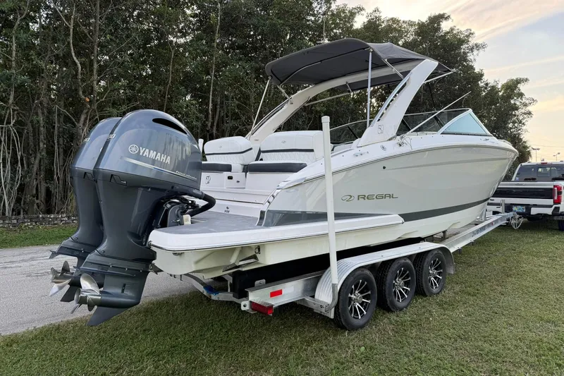 Slide: The Image of 2021 Regal 29 OBX boat on trailer with Yamaha outboard motor, parked on grass. - 2