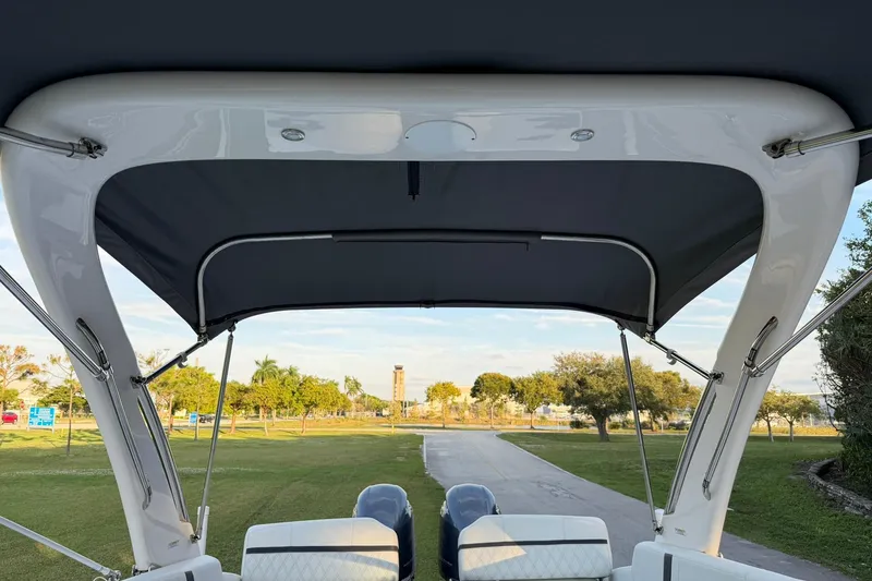 Slide: The Image of 2021 Regal 29 OBX boat with canopy, parked on a scenic grassy area. - 28