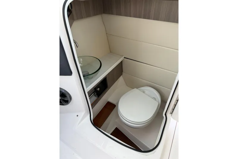 Slide: The Image of 2021 Regal 29 OBX boat interior bathroom with toilet and glass sink. - 29