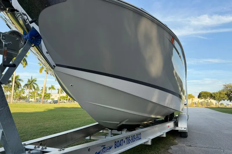 Slide: The Image of 2021 Regal 29 OBX boat on trailer, parked outdoors with palm trees in background. - 7
