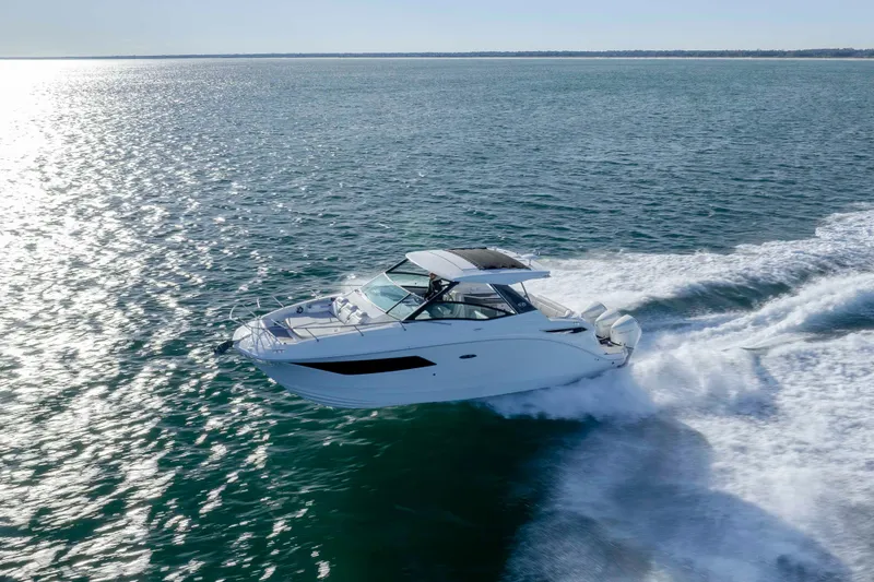 Slide: The Image of 2020 Sea Ray Sundancer 320 Outboard cruising on open water, creating a wake. - 14