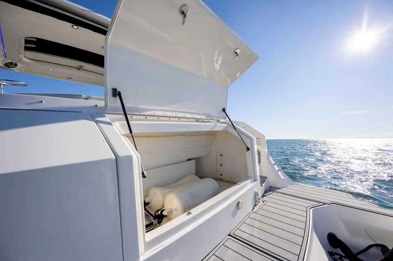 Slide: The Image of 2020 Sea Ray Sundancer 320 Outboard storage compartment open on sunny ocean day. - 30