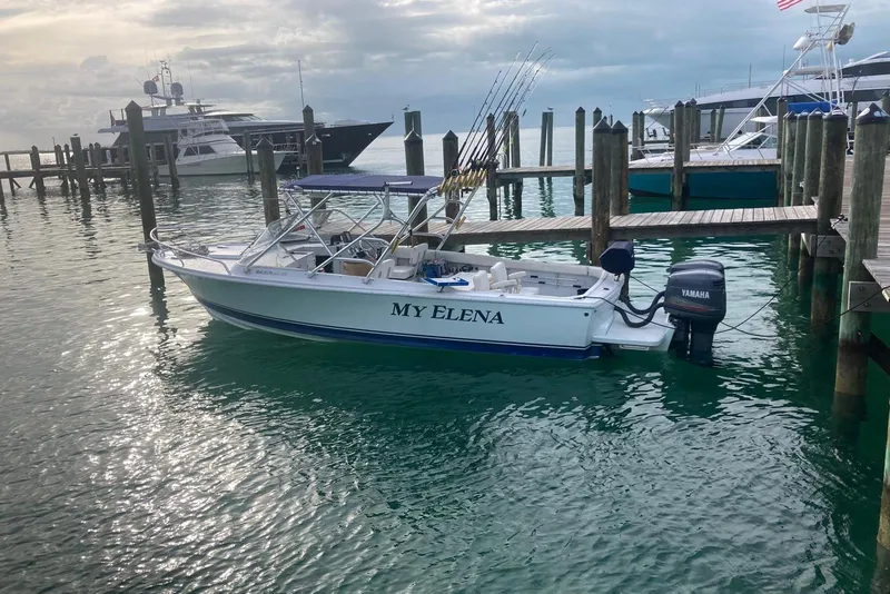 The Image of 1962 Bertram 25 Moppie boat named "My Elena" docked in a marina with fishing rods. - 0