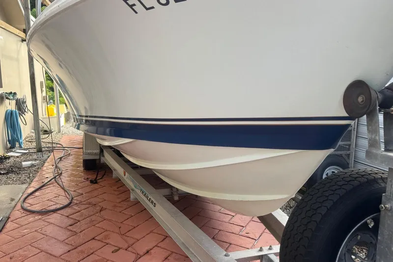 Slide: The Image of 1962 Bertram 25 Moppie boat on trailer, showcasing hull design and blue stripe. - 9