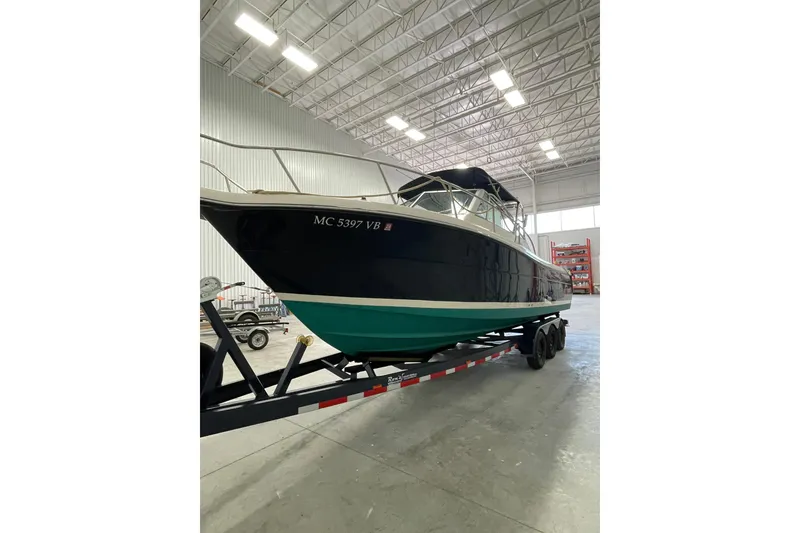 Slide: The Image of 2002 Pursuit 2860 Denali boat interior with seating and steering wheel in a storage facility. - 2