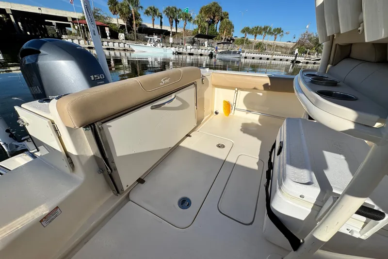 Slide: The Image of 2022 Scout 215 XSF boat interior with Yamaha 150 engine, docked by palm trees. - 12
