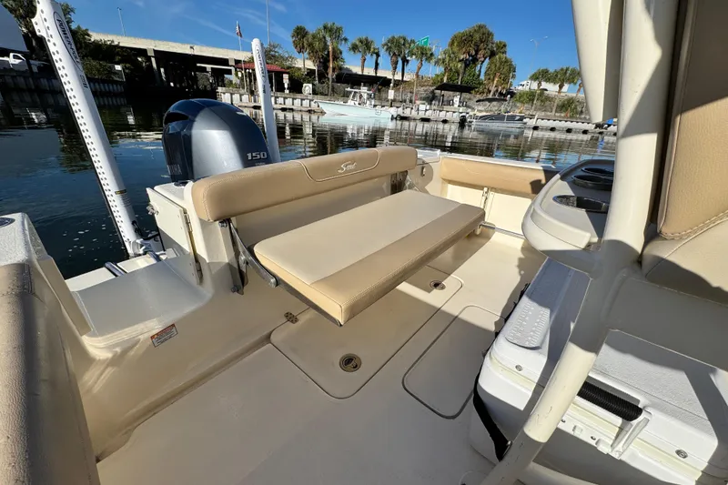 Slide: The Image of 2022 Scout 215 XSF boat interior with seating and engine, docked by water. - 13