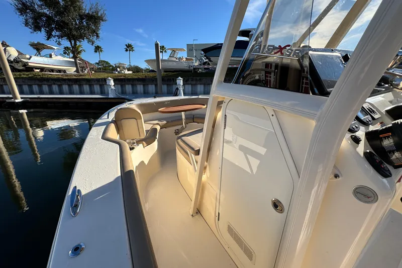 Slide: The Image of 2022 Scout 215 XSF boat interior with seating and console, docked under clear blue sky. - 19