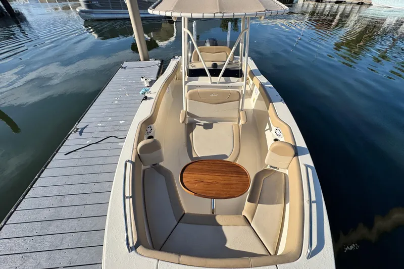 Slide: The Image of 2022 Scout 215 XSF boat with seating and table, docked on calm water. - 21
