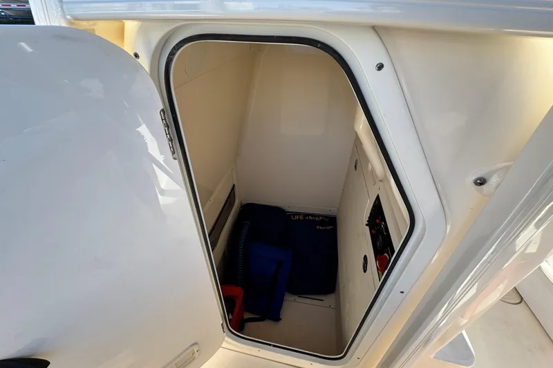 Slide: The Image of 2022 Scout 215 XSF boat storage compartment with safety equipment and controls. - 23