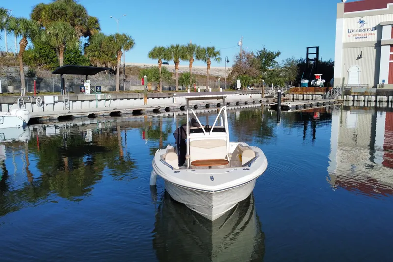 Slide: The Image of 2022 Scout 215 XSF boat docked at marina with palm trees and clear blue sky. - 6