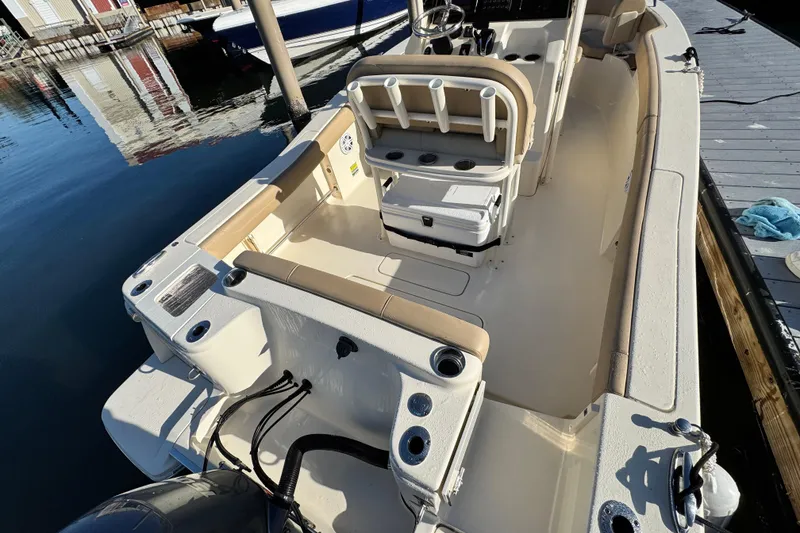 Slide: The Image of 2022 Scout 215 XSF boat interior with seating and console, docked by the water. - 9