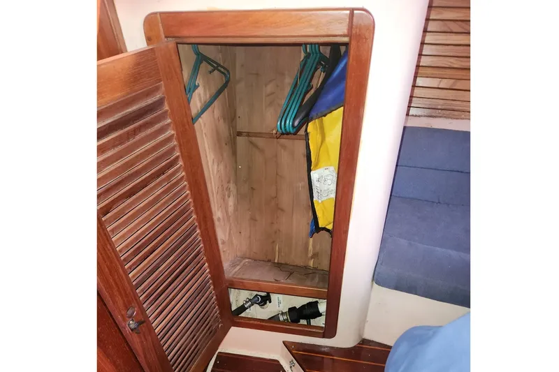 Slide: The Image of Wooden closet interior on 1993 Catalina Morgan 381 sailboat with hangers and life jacket. - 23